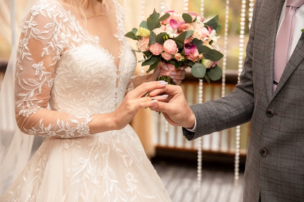 Wedding ceremony. Groom puts a wedding ring on bride's finger