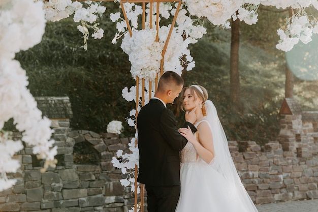 Wedding ceremony. Happy bride, groom and bridesmaids near beautiful wedding arch