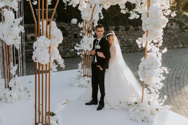 Wedding ceremony. Happy bride, groom and bridesmaids near beautiful wedding arch