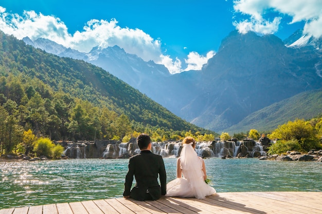 Wedding couple, Bride and groom watch the waterfall mountian sitting on wooden bridge