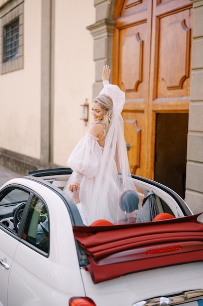 Wedding couple in a convertible the bride is dancing on the seat the groom is driving a car wedding