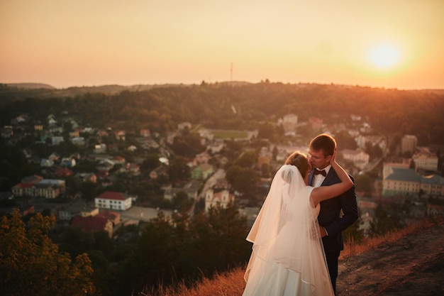 Wedding couple embracing at sunset