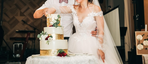 Wedding couple is cutting the cake Beautiful tasty dessert decorated with flowers