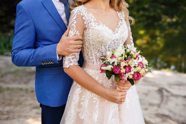 Wedding couple in love. Groom embrace bride with wedding bouquet