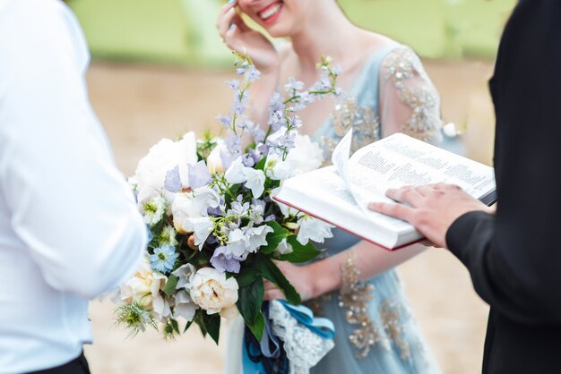 Wedding couple near the ocean with a priest