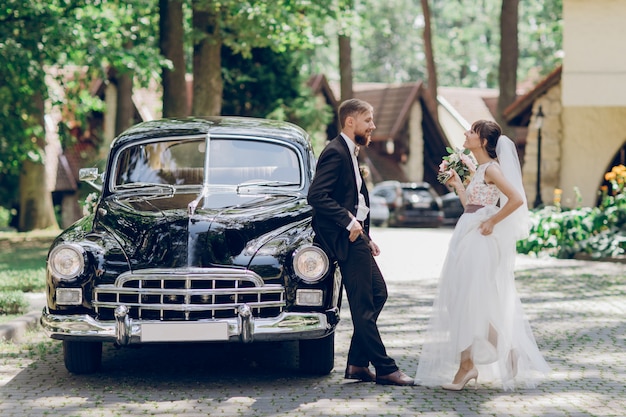 Wedding couple and retro car in the park