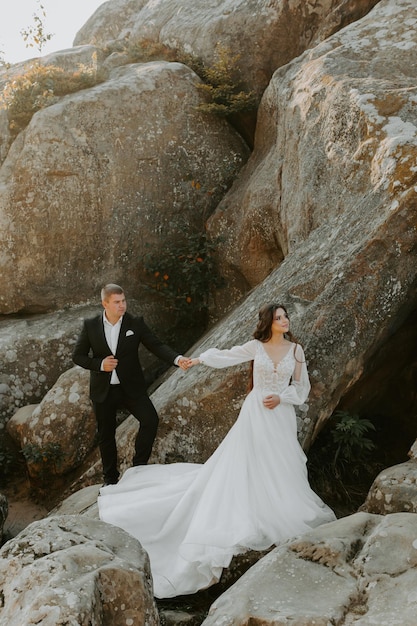 Wedding couple. Standing face to face with the green hills on background.