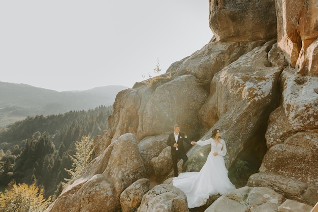 Wedding couple. Standing face to face with the green hills on background.