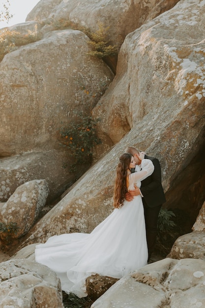 Wedding couple. Standing face to face with the green hills on background.