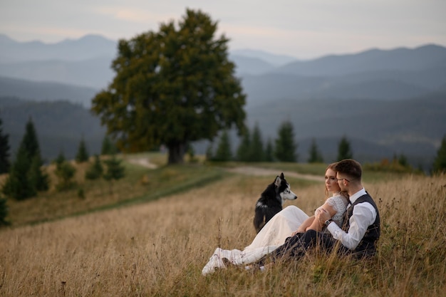 Wedding couple with dog in mountains at sunset romantic evening in mountains