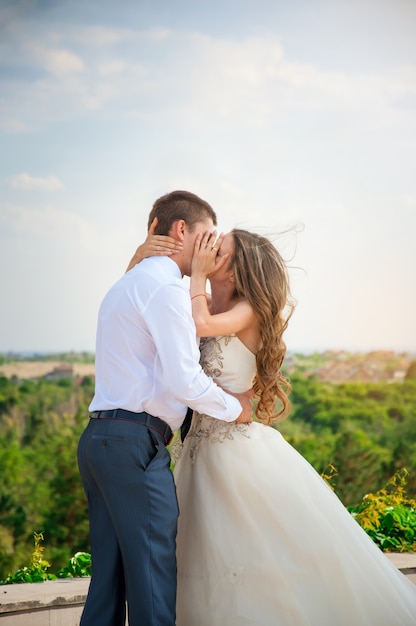 Wedding Day. Beautiful Bride in White Dress with Groom. Happy Kissing Couple