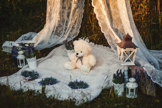 Wedding decorations. Teddy bear on a white blanket. Flowers