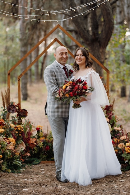 Wedding dinner of a newlywed couple in the autumn forest on the background of the wedding ceremony