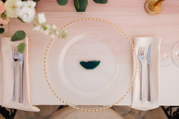 Wedding dinner table reception closeup of wildcard with gold beads transparent glass runner of pink