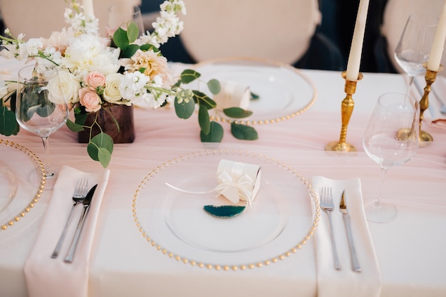 Wedding dinner table reception closeup of wildcard with gold beads transparent glass runner of pink