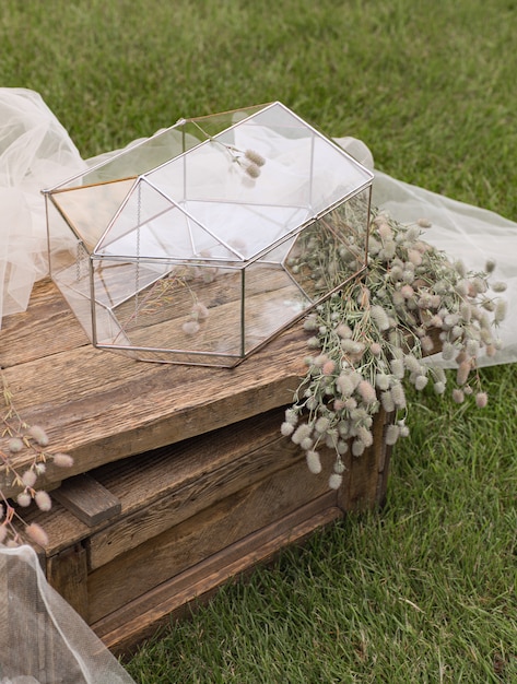 Wedding glass box for envelopes for greetings on little wooden table and the  white tissue with plants as a decoration