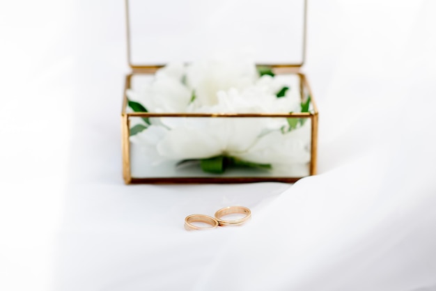 Wedding gold rings on the background of a glass box on a background of white fabric concept for event agencies