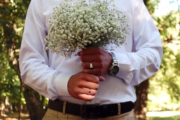 A wedding is a troublesome business a delicate bouquet in the hands of the groom against the background of elegant clothes closeup space for text