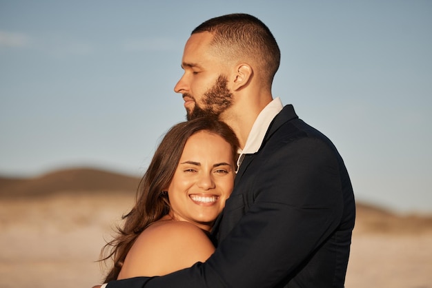 Wedding love and happy with couple at sunset and hug together for celebration event or beach venue Smile support and commitment with man and woman holding in embrace for marriage goals and trust