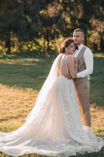 Wedding photo The bride and groom are standing in a beautiful forest and beautiful light hugging Couple in love Stylish groom Portrait