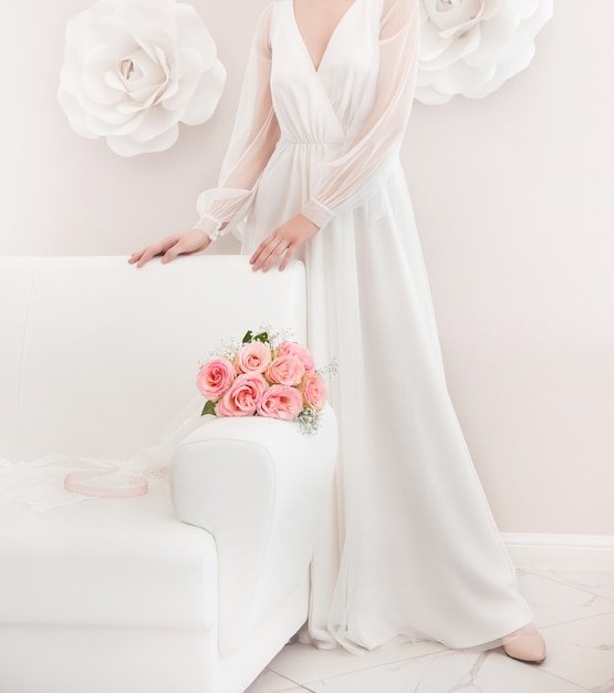 wedding photo with a white dress and a bouquet of pink roses on a light background