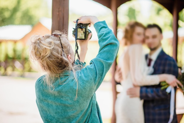 A wedding photographer photographs a couple in nature on a sunny day