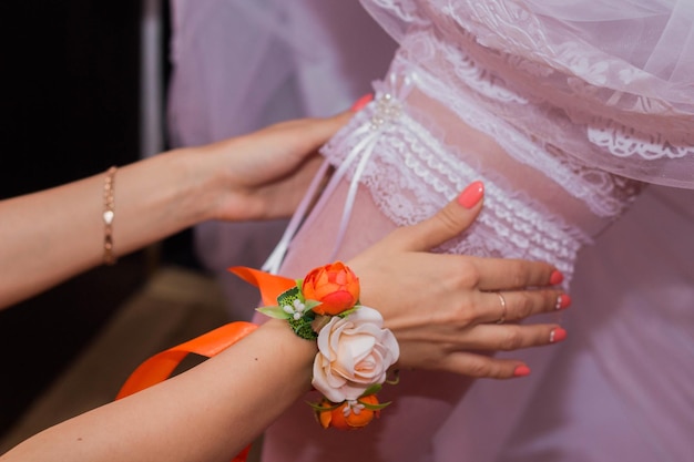 Wedding preparations Bridesmaid is helping the bride to dress stockings on foot Bride is adjusting white garter on her leg