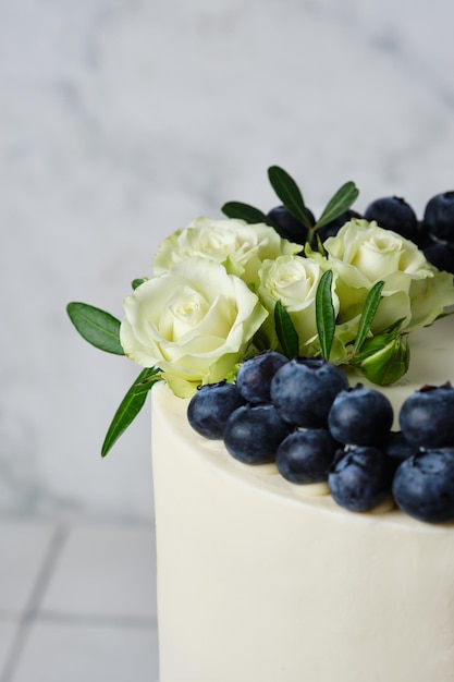 Wedding preparations White wedding cake decorated with fresh blueberries and flowers