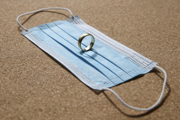 A wedding ring on a medical face mask. Divorce and marriage separation concept image.