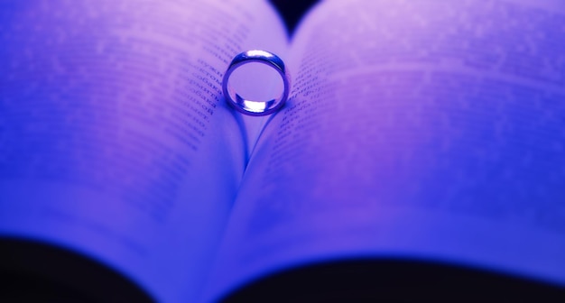 Wedding ring in open book and heartshaped shadow  Concept of Valentine's Day