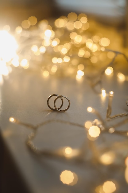 Wedding rings on blured bokeh glowing golden background Symbol of love and romance on a textured glitter background with copy space for your greeting or congratulations