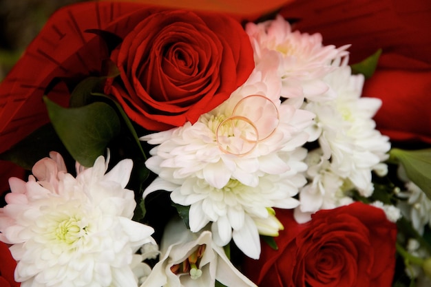 Wedding rings on a chrysanthemum flower surrounded by roses