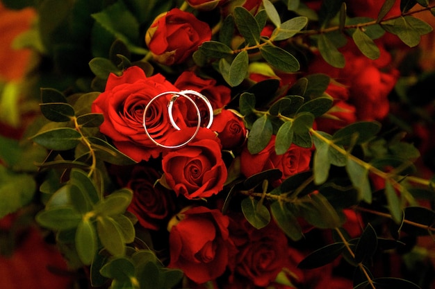 Wedding rings lie on rose flowers in a bouquet