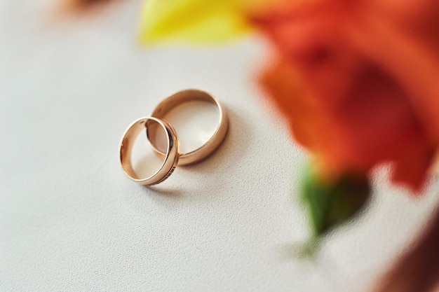 Wedding rings lie on the table near a wedding bouquet