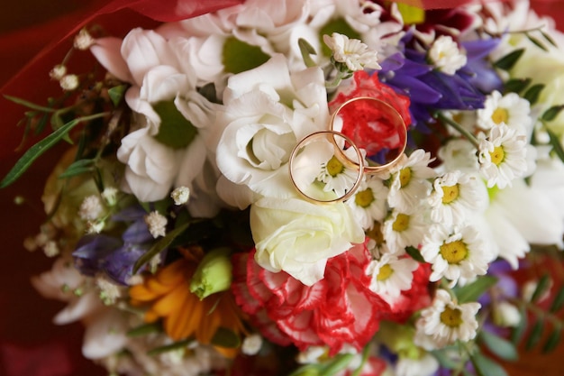 Wedding rings lie on a wedding bouquet of flowers