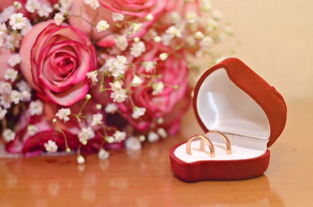 Wedding rings in a pink box next to the bride's bouquet