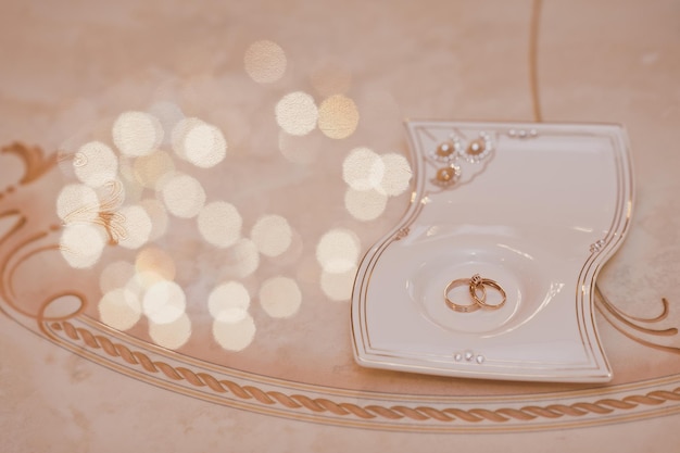 Wedding rings on a stand on the table surrounded by light glare 2658