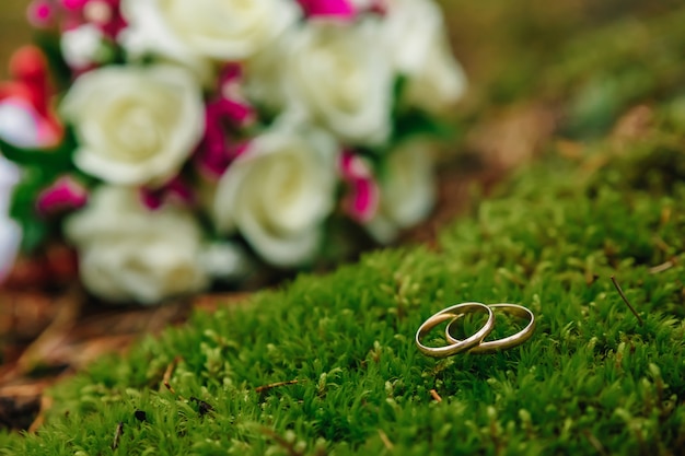 Wedding rings with bridal bouquet lying on the morning of the bride.