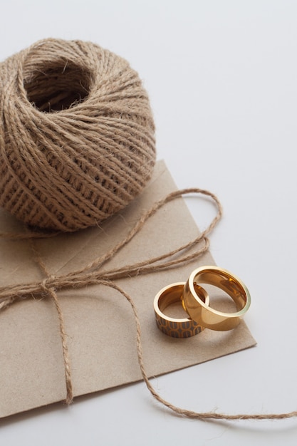 Wedding rings with invitation and brown thread