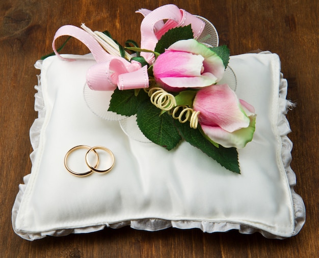 Wedding rings with roses on bridal pillow