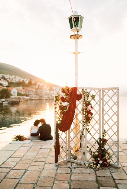 Wedding screen stands on the pier with the bride and groom hugging in the background