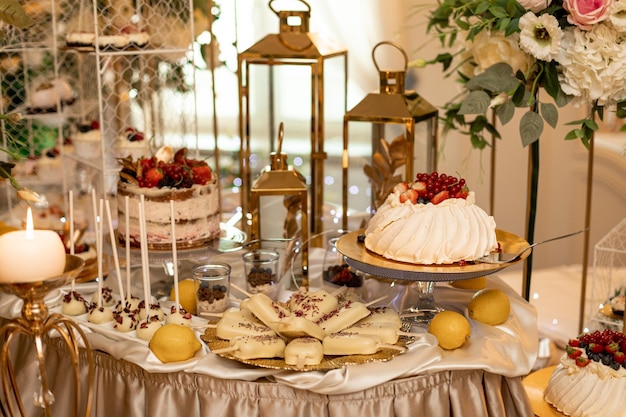 Wedding sweet table with cake and various desserts decorated with flowers. Buffet with delicious pastries. Delicious wedding buffet with cupcakes. Festive event. Organization weddings.