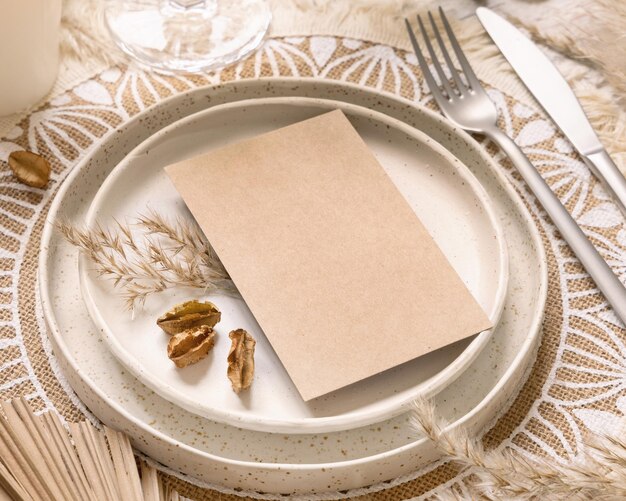 Wedding table place with blank card on bohemian placemat close up. Boho wedding card mockup. Tropical beige template with dried palm leaves and pampas grass, place fot text