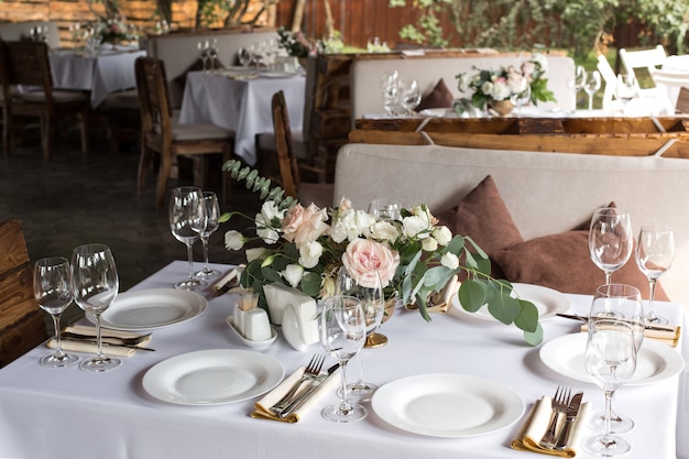 Wedding table setting decorated with fresh flowers. Banquet table for guests outdoors with a view of nature