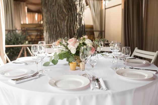 Wedding table setting decorated with fresh flowers in a brass vase