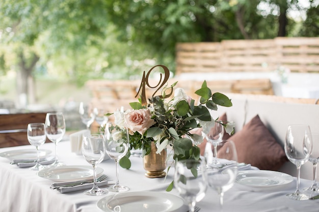 Wedding table setting decorated with fresh flowers in a brass vase