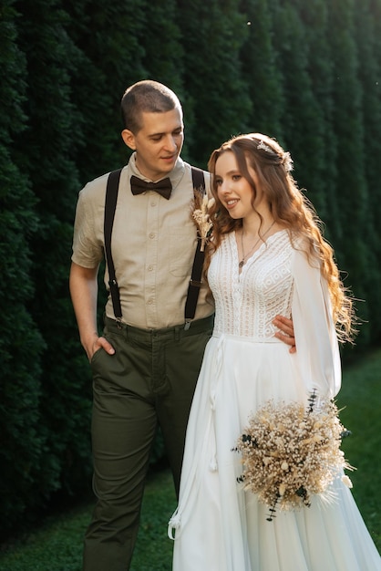 wedding walk of the bride and groom in a coniferous park in summer