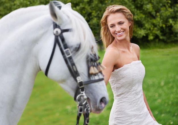 Wedding woman and happy with horse outdoor on grass for celebration marriage or confidence in countryside Bride person and stallion on lawn in field with smile dress or animal at event in nature