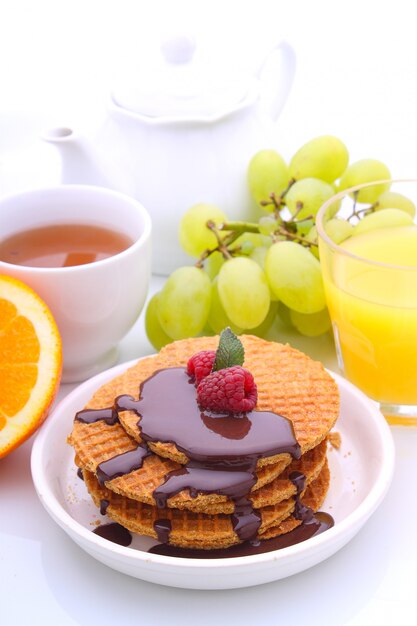 Weekend breakfast: waffles with chocolate and raspberries, grapes, tea and orange juice