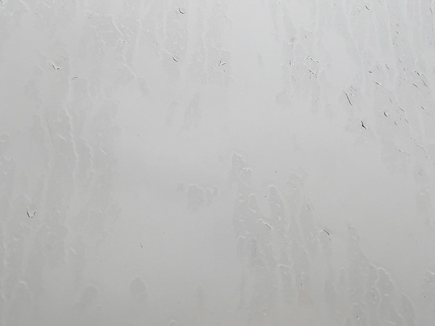 Weeping window in rainy cloudy weather outside on street Close up Raindrops streaming down window It's raining Texture of window glass with streaks